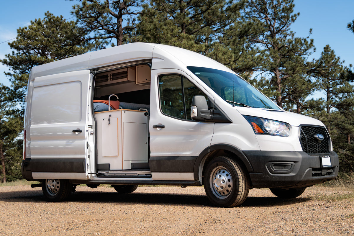 Timber Rambler van — Ford Transit exterior with the sliding door open among pine trees