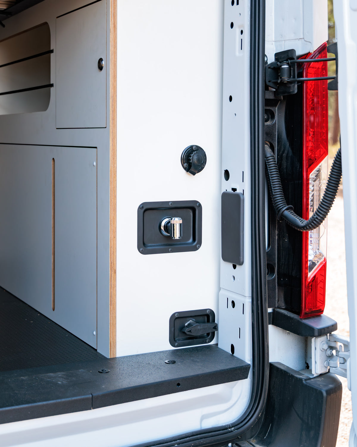 Rear hookups — shore power, 12V outlet and spray-down shower port by the rear door