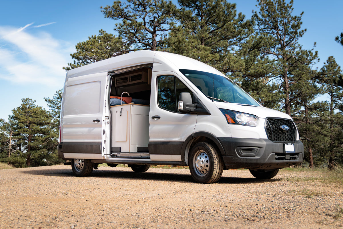 Timber Rambler van — Ford Transit exterior with the sliding door open among pine trees